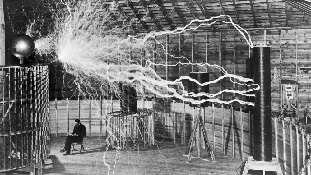 Nikola Tesla sentado calmamente entre suas bobinas com milhões de volts, no laboratório em Colorado Springs