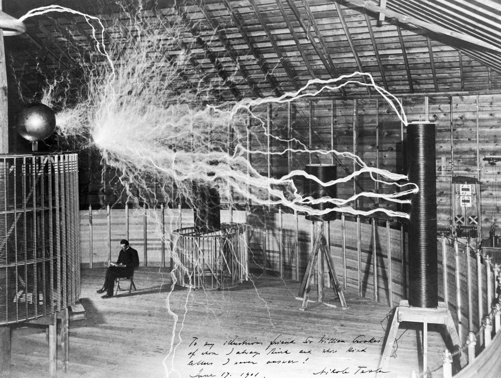 Nikola Tesla sentado calmamente entre suas bobinas com milhões de volts, no laboratório em Colorado Springs
